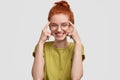 Use your brain. Happy red haired girl holds both index fingers on temples, tries to think before acting stupidly Royalty Free Stock Photo