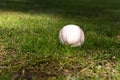 Used baseball laying on green grass on baseball field.