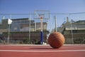 Used basketball in the foreground lies on a basketball court and a basketball basket with a blurred background