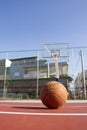 Used basketball in the foreground lies on a basketball court and a basketball basket with a blurred background