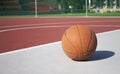 Used basketball in the foreground lies on an empty basketball court with a blurred background