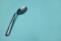 A used and bent spoon, on a blue background.