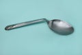 A used and bent spoon, on a blue background.