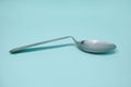 A used and bent spoon, isolated on a blue background.