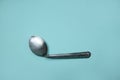 A used and bent spoon, isolated on a blue background.