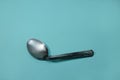 A used and bent spoon, isolated on a blue background.