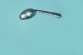 A used and bent spoon, isolated on a blue background.