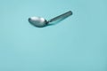 A used and bent spoon, isolated on a blue background.