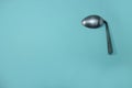 A used and bent spoon, isolated on a blue background.