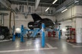 Used black car Porsche Cayenne with an open hood raised on a four-post lift for repairing the chassis and engine in a vehicle