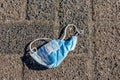 Used blue face mask lying on the ground on a rural cobblestone street