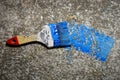 Used blue paint brush on concrete surface. There is a blue trace of paint from the brush. Unwashed wooden brush for painting the