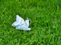 A used, blue surgical face mask used for COVID-19 PPE protection, discarded as litter on grass Royalty Free Stock Photo