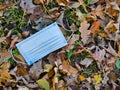 A used, blue surgical mask used for COVID-19 PPE protection, discarded as litter in a rural area Royalty Free Stock Photo