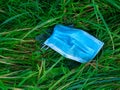 A used, blue surgical mask used for COVID-19 PPE protection, discarded as litter in rural countryside Royalty Free Stock Photo
