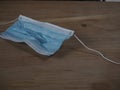 Used and broken 3-ply blue surgical mask to cover the mouth and nose with rubber ear straps. Protection mask from bacteria and