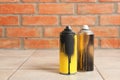 Used cans of spray paint on floor against brick wall. Royalty Free Stock Photo