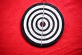 Used dart board standing on red carpet background