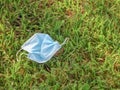 A used, discarded face mask laying in the grass.