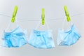 Used disposable protective surgical masks drying on a clothesline with green clothespins on a white background. Royalty Free Stock Photo