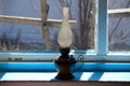 Used flat-wick kerosene lamp also known as a paraffin lamp on old shabby blue windowsill in the sunlight Royalty Free Stock Photo