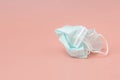 Used green medical face mask was crumpled on old rose background. The concept of rejection or disposal mask after quarantine Royalty Free Stock Photo