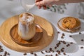 Used hand pouring creamy milk into a brewing iced coffee is served with cookies. Cold coffee drink glass with ice and cream milk Royalty Free Stock Photo
