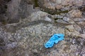 Used medical gloves on the stone. Blue crumpled disposable glove dumped on the ground