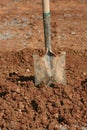 Used, muddy shovel standing in pile of dirt.