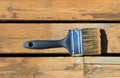 Used paintbrush filled with wood stain on a natural cedar deck Royalty Free Stock Photo