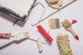 Used painting tools with red handles covered in warm white paint layed out in a composition on a plain white background