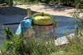 Used partially rusted yellow electric concrete mixer with dried concrete behind wire fence