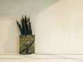 Used pencils in pencil holder against concrete wall background