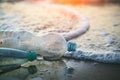 Used plastic bottles on sandy beach at morning or sunset light