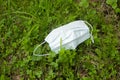 Used protective mask lying on the grass. The concept of recovery, the end of the pandemic, quarantine Royalty Free Stock Photo