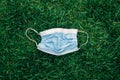 Used sanitary mask lying on grass ground. Disposable recyclable face mask flat lay. Coronavirus, medicine, seasonal allergy