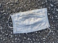 Used surgical mask smashed by traffic in a parking lot