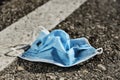 Used surgical mask thrown on the asphalt