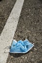 Used surgical mask thrown on the asphalt