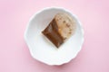 Used tea bag in a white bowl. Pink background.