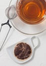 Used teabag on ceramic plate with glass of tea and strainer infuser on white Royalty Free Stock Photo