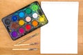 Used watercolor paints, brushes for painting and blank white paper sheet on wooden background. Top view. Royalty Free Stock Photo