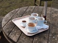 used white cups on tray on wooden table outside cafe close up