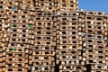 Used wooden pallets stacked on top of each other along a wall of recycled lumber for cargo loading and transportation. A pile of