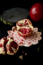 Useful antioxidant pomegranate, lies with the dark countertops. One in broken with juicy flesh.Framed by green leaves