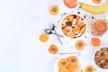 Useful breakfast with ingredients, flat lay, fruit salad with granola, apricots, bananas, honey and peaches on a bright table. The Royalty Free Stock Photo