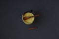 Useful golden coconut milk in a cup with turmeric in a wooden spoon on a gray background. Top view