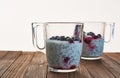 Useful and nourishing breakfast, pudding of currant berries, cherries with yoghurt and chia seeds in glass cups on wooden backgrou