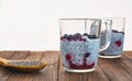 Useful and nourishing breakfast, pudding of currant berries, cherries with yoghurt and chia seeds in glass cups on wooden backgrou