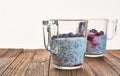 Useful and nourishing breakfast, pudding of currant berries, cherries with yoghurt and chia seeds in glass cups on wooden backgrou